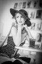 Fashionable attractive lady with hat and scarf sitting in restaurant, indoor shot. Young woman posing in elegant scenery Royalty Free Stock Photo