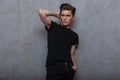Fashionable attractive young man model with a stylish hairstyle in a trendy black t-shirt in vintage jeans with a nose piercing Royalty Free Stock Photo