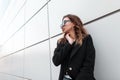 Fashionable attractive young women hipster in an elegant black coat in a T-shirt in jeans in stylish sunglasses Royalty Free Stock Photo