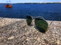 Fashionable aviator sunglasses with dark lenses and gold frames sit on a granite stone pier and reflect the sun& x27;s rays Royalty Free Stock Photo