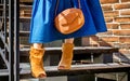 Fashionable bag close-up in female hands.Girl walks in the city outdoors. Stylish modern and feminine image, style. Bright orange Royalty Free Stock Photo