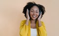 Fashionable Beautiful African American woman enjoy listening favorite music in headphones, closing her eyes from pleasure, music