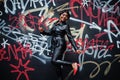 Fashionable beautiful african american woman posing in black leather jacket and pants at street against graffiti wall Royalty Free Stock Photo