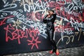 Fashionable beautiful african american woman posing in black leather jacket and pants at street against graffiti wall Royalty Free Stock Photo