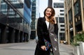 Fashionable beautiful woman walking at the street. Stylish girl dressed in the fur coat and clutch Royalty Free Stock Photo