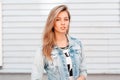 Fashionable beautiful young woman in a fashionable blue denim jacket in a stylish white t-shirt is standing on the street Royalty Free Stock Photo