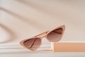 Fashionable beige cat eye frame sunglasses on beige background. Women\'s Trendy sunglasses still life in minimal stile.