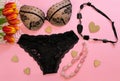 Fashionable black lace woman lingerie composition with red tulip flowers black and pink necklace and wooden hearts on pink
