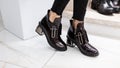 Fashionable black patent leather shoes with silver heel on female legs. Beautiful design of the new autumn-spring collection