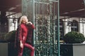 fashionable blonde girl with a red lipstick posing outdoors . Dressed in a red leather leggings, turtleneck and Royalty Free Stock Photo