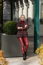 A beautiful, modern, fashionable blonde girl with a red lipstick posing outdoors . red leather leggings, turtleneck and Royalty Free Stock Photo