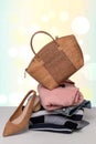 A fashionable brown luxury oak cork women`s handbag on a pile of folded women`s clothing and a single shoe on the table over Royalty Free Stock Photo