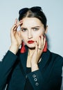 Fashionable brunette woman posing in trendy look. Black jacket, black swimsuit, sunglasses and red earrings. Royalty Free Stock Photo