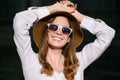 Fashionable business woman in sunglasses and hat enjoying the sun while standing outdoors, smiling happily with Royalty Free Stock Photo