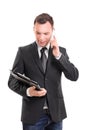 Fashionable businessman looking at clipboard and talking on mobile phone Royalty Free Stock Photo