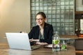 Fashionable caucasian businesswoman with glasses sitting at the desk and looking at the window. Stylish businesswoman working at