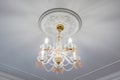 Fashionable chandelier in a bright interior hanging under ceiling in palace, apartment or hotel