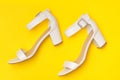 Fashionable concept. White shoes on yellow background, top view