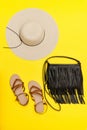 Fashionable concept. Women`s beach hat, handbag, sandals. Yellow background Royalty Free Stock Photo