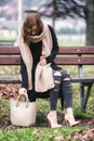 Fashionable dressed woman large scarf sitting lonely on bench in park