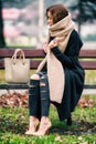 Fashionable dressed woman large scarf sitting lonely on bench in park