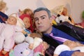 Fashionable eccentric man with many dolls and toys in bed Royalty Free Stock Photo