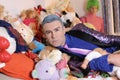 Fashionable eccentric man with many dolls and toys in bed Royalty Free Stock Photo