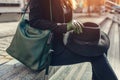 Fashionable female accessories. Woman with green handbag wearing gloves and holding black hat outdoors Royalty Free Stock Photo