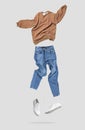 Fashionable flying brown cotton stylish sweatshirt, blue jeans, leather sneakers isolated on gray background. Clothes, shoes, Royalty Free Stock Photo