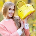 Fashionable girl in a coat holding leather bag bright yellow in autumn Royalty Free Stock Photo