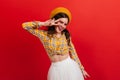 Fashionable girl in great mood posing on red background. Woman in orange beret shows peace sign. Royalty Free Stock Photo