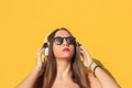 Listening music in her headphones with yellow background