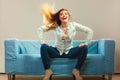 Fashionable girl wearing denim relaxing on couch. Royalty Free Stock Photo