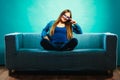 Fashionable girl wearing denim sitting on couch. Royalty Free Stock Photo