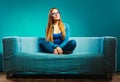 Fashionable girl wearing denim sitting on couch. Royalty Free Stock Photo