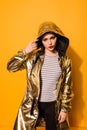 Fashionable girl wearing shining gold coat with hood on the yell Royalty Free Stock Photo