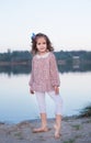 The fashionable girl in white trousers near the lake. The child costs barefoot on sand