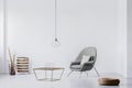 Grey colored armchair with pillow next to industrial coffee table in chic living room interior