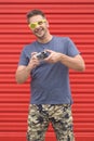 Portrait of hipster guy holding vintage camera on red background. Royalty Free Stock Photo