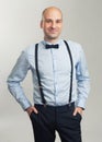 Fashionable handsome bald man in suspenders and butterfly tie Royalty Free Stock Photo