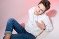 Fashionable handsome young European male model dressed in white sweatshirt, blue jeans and white sneakers posing in studio on a Royalty Free Stock Photo