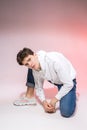 Fashionable handsome young European male model dressed in white sweatshirt, blue jeans and white sneakers posing in studio on a Royalty Free Stock Photo