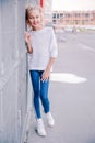 Fashionable and happy teen girl posing against a background of a building and lattice