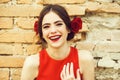 Fashionable happy woman in red dress with rose in hair