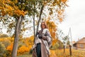 Fashionable happy young woman hipster in stylish glasses in trendy autumn outerwear with a vintage knitted scarf rests on the Royalty Free Stock Photo