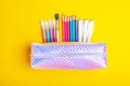 Fashionable sparkling pencil case with multicolored felt-tip pens, pencils, brush and pens on bright yellow background. Royalty Free Stock Photo