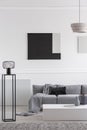 Fashionable industrial black lamp next to scandinavian sofa in bright living room