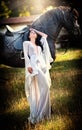 Fashionable lady with white bridal dress near brown horse. Royalty Free Stock Photo