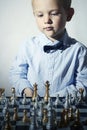 Fashionable Little boy playing chess.Little genius Child. Intelligent game.Chessboard