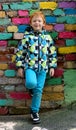 Fashionable little boy. Red-haired handsome kid. Model wearing trendy jacket posing against colorful brick wall Royalty Free Stock Photo